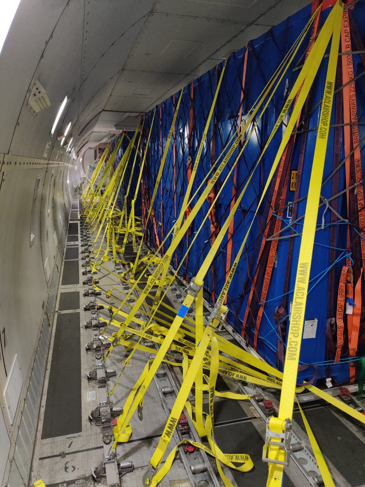 Yellow cargo straps securing a blue pallet inside a freighter main deck