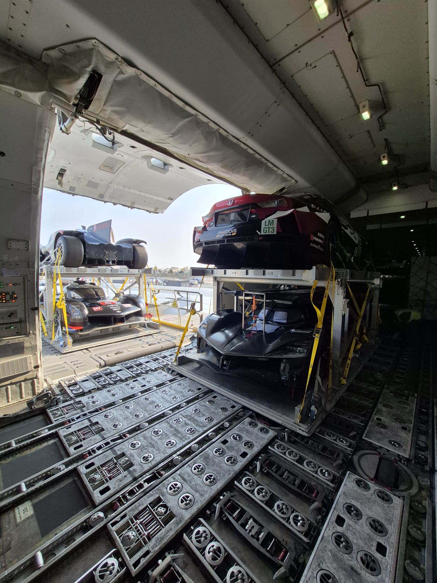 Race cars on double-stacked pallets inside a freighter cargo hold